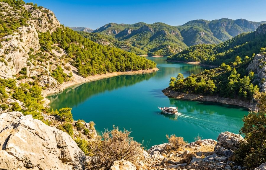 Изумрудное водохранилище между сосновыми склонами, по воде идёт белая прогулочная лодка