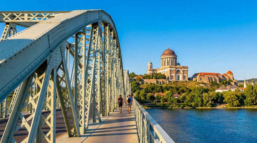 Пешеходная дорожка вдоль стальных арок моста через Дунай, за рекой на холме — базилика Эстергома